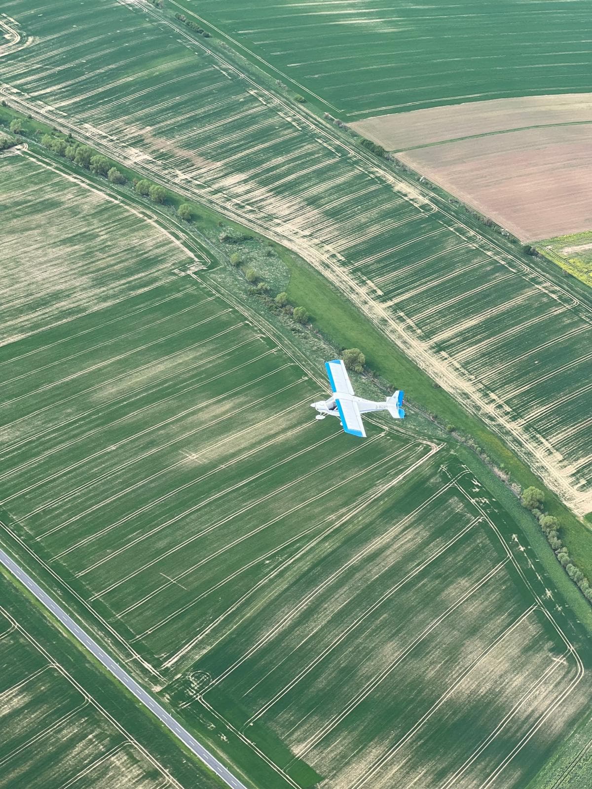 Ultraleichtflugzeug im Flug über grünen Feldern