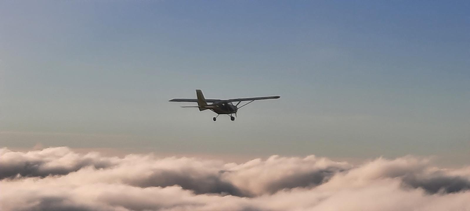 Ultraleichtflugzeug über einer Wolkendecke